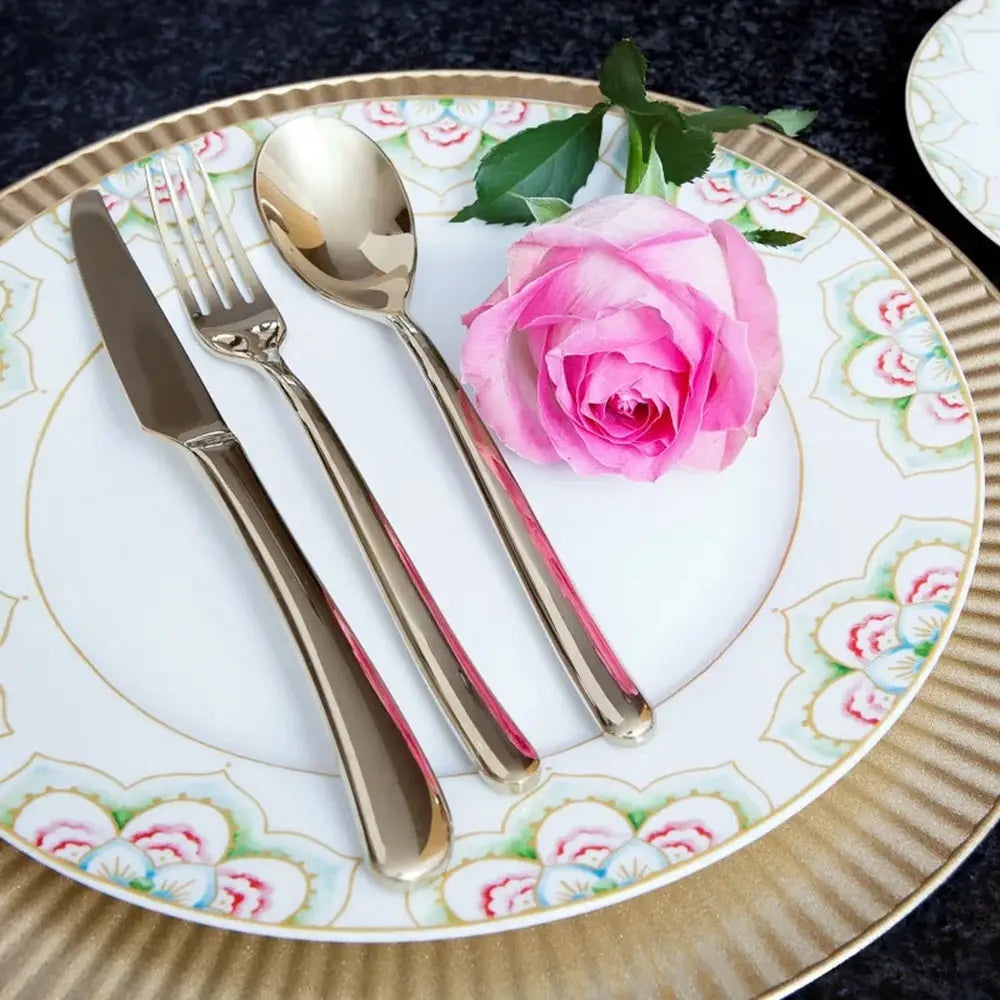 Decorative plate with floral rim, silver cutlery, and a pink rose.
