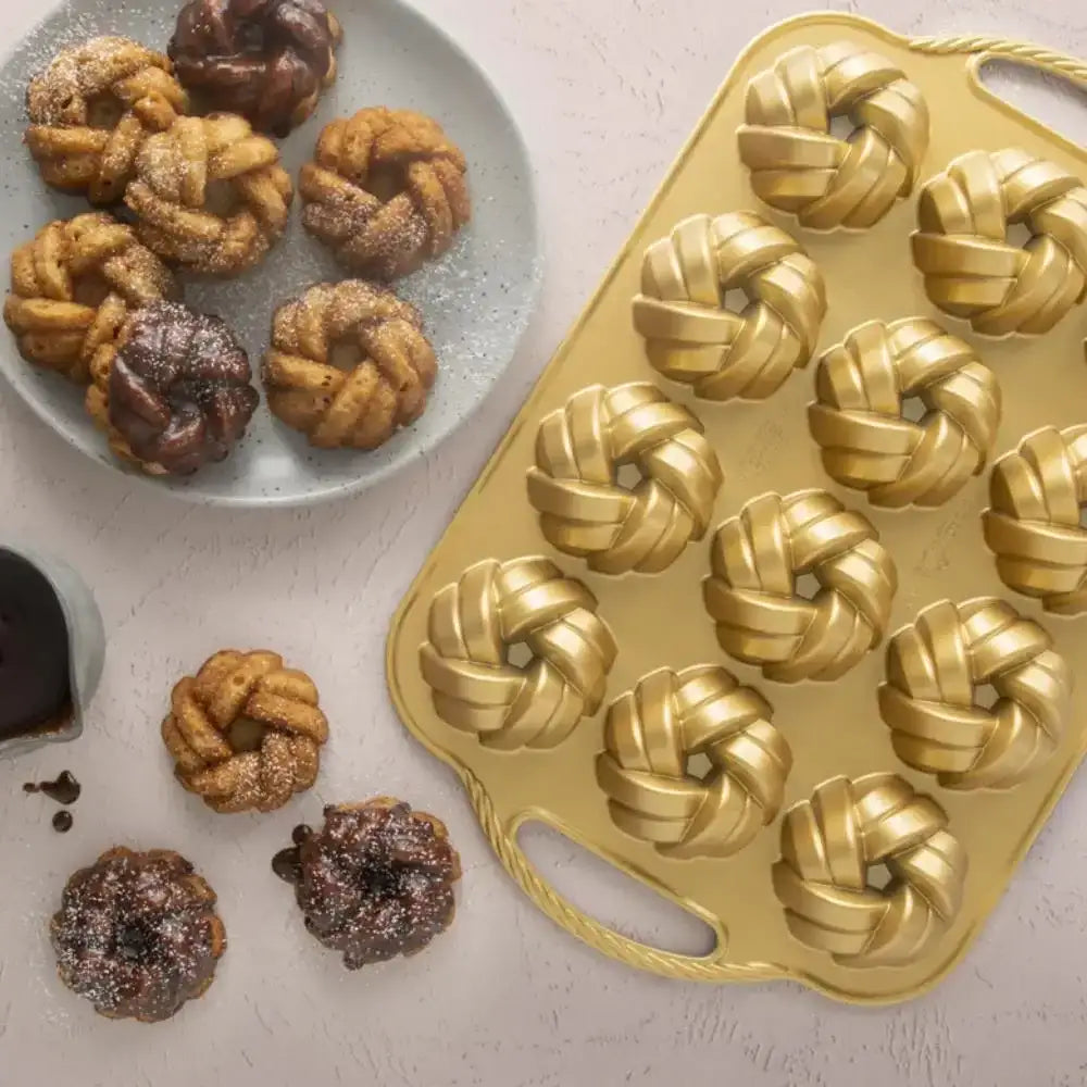 Braided mini Bundt cakes on a plate and countertop with a gold nonstick baking pan, Cookin Stores kitchenware