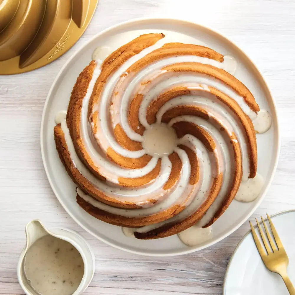 Golden-brown bundt cake with white glaze served on a plate made using nordic ware gold heritage bundt pan cast aluminum