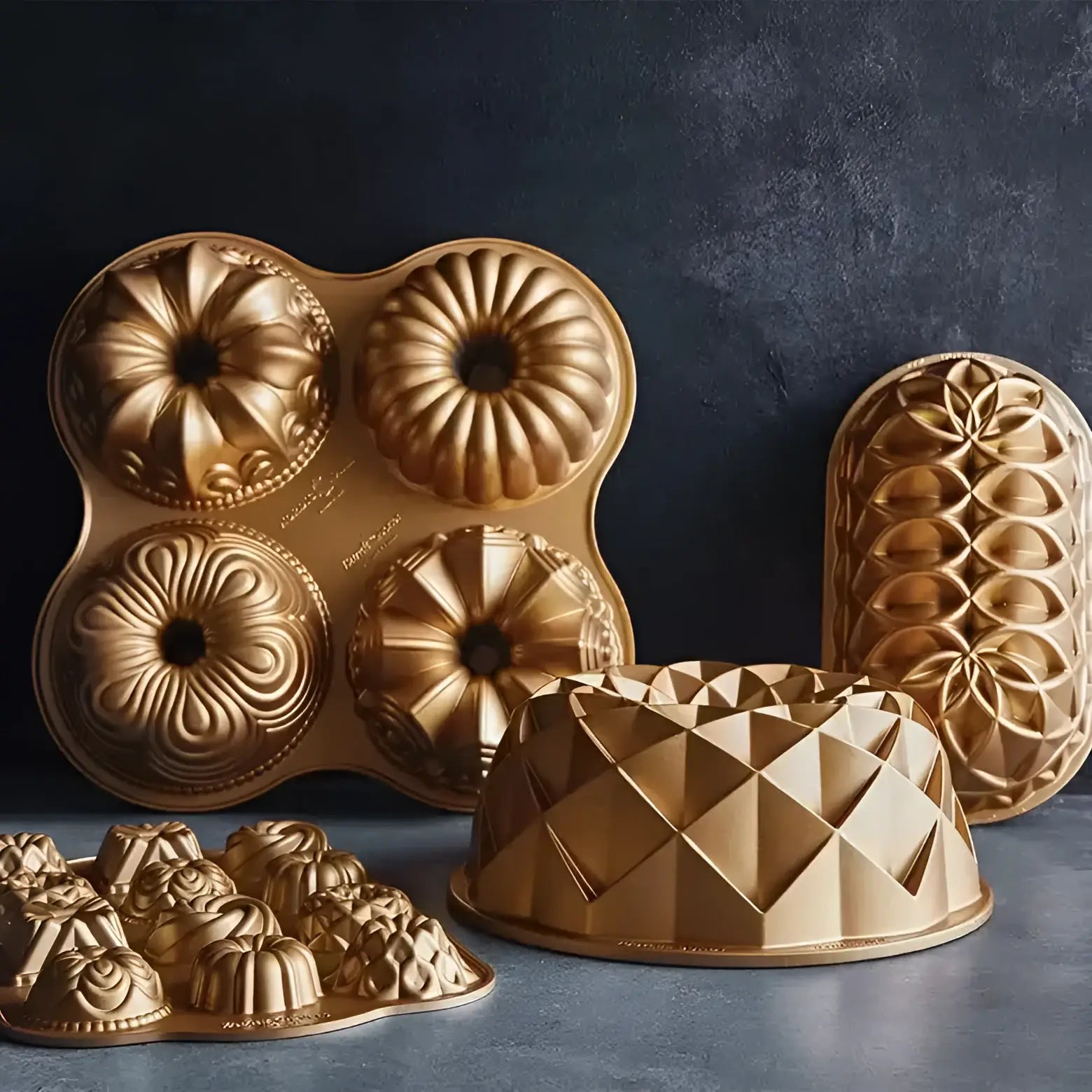 Collection of gold Bundt cake molds on a dark background