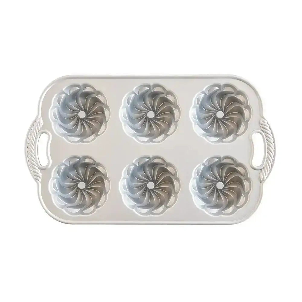 Metal muffin tin with six cupcake liners on a white background