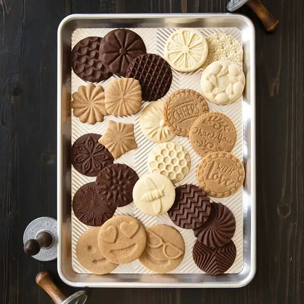 Assorted cookies on a baking tray with a wooden surface