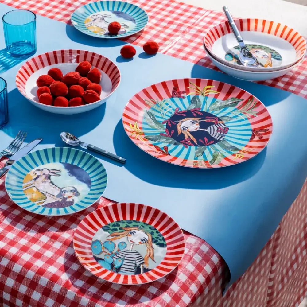 Colorful tableware with artistic designs on a blue tablecloth and red checkered tablecloth.