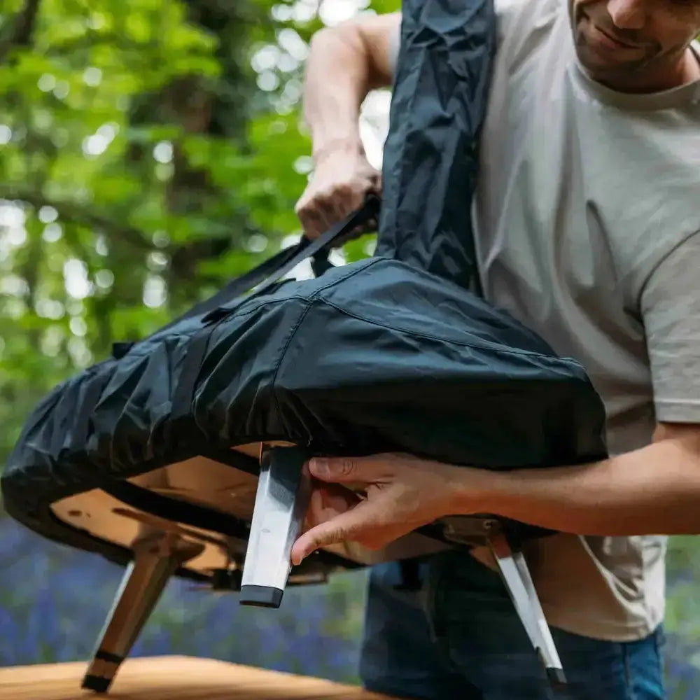 Person holding a portable chair with a forest background