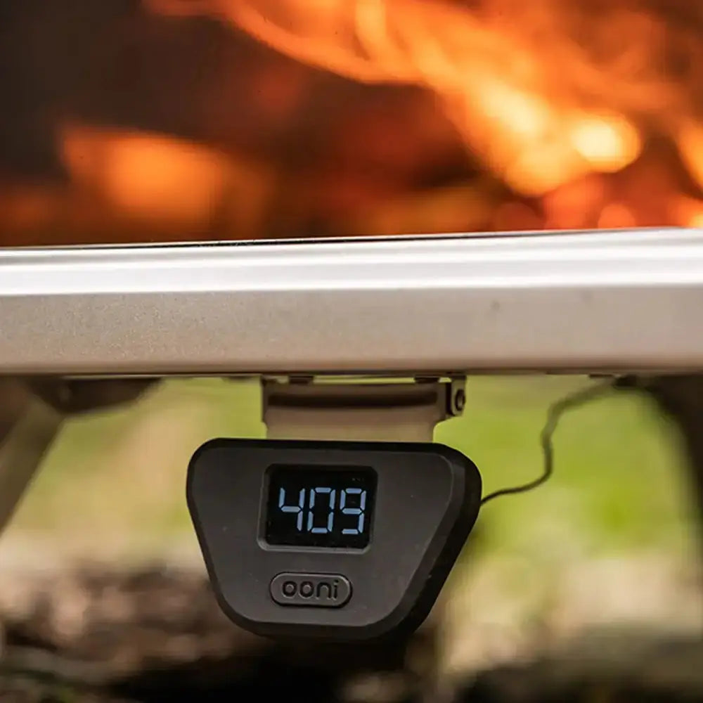 Digital thermometer attached to a grill with flames in the background