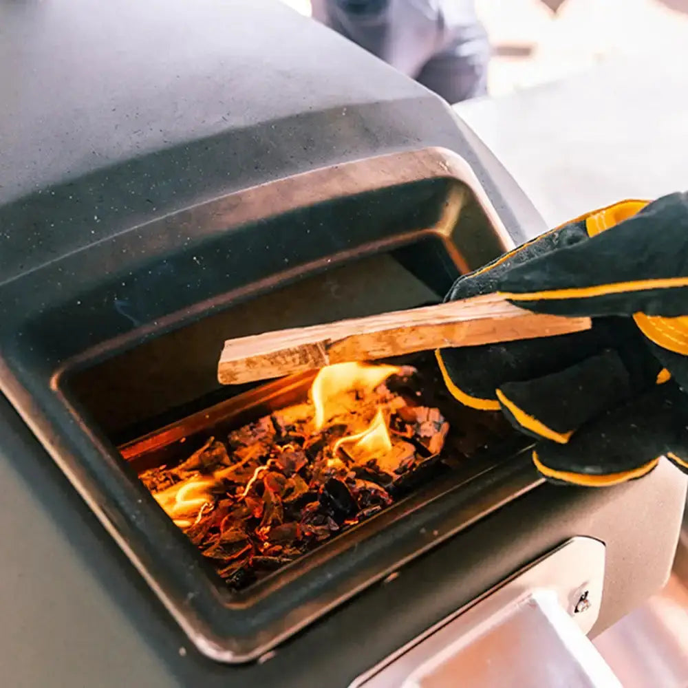 Person using a glove to add wood into a firebox with flames visible