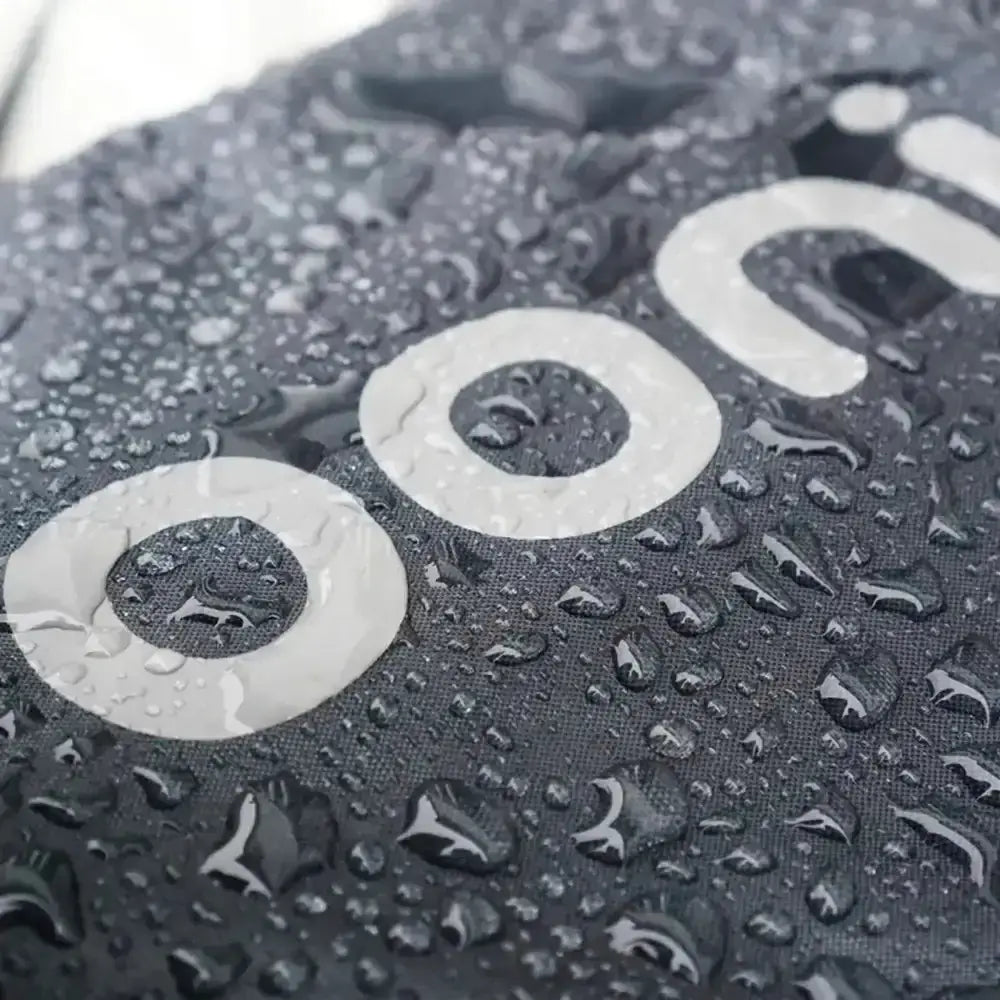 Black fabric pizza oven cover with white circular logo and water droplets for ooni karu pizza oven protection