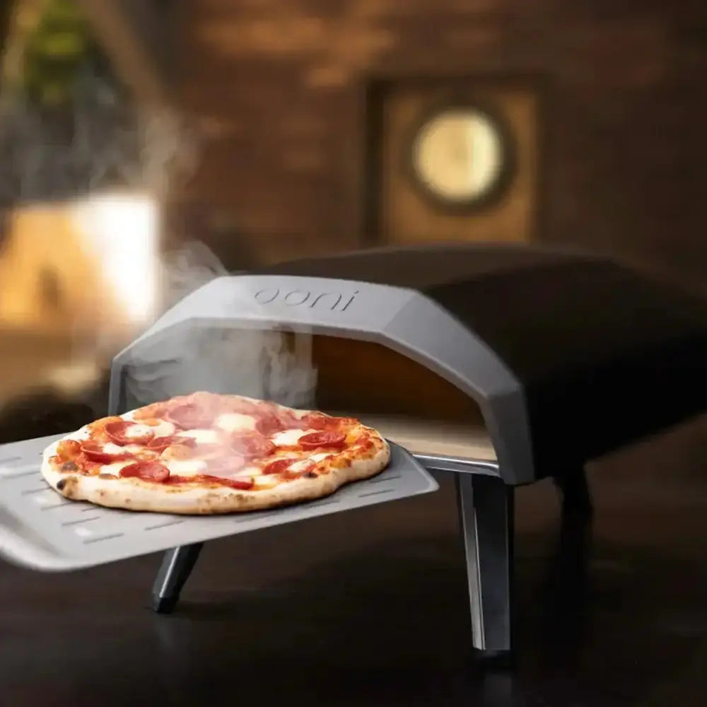 Portable pizza oven with a pizza inside, set against a warm-toned background.