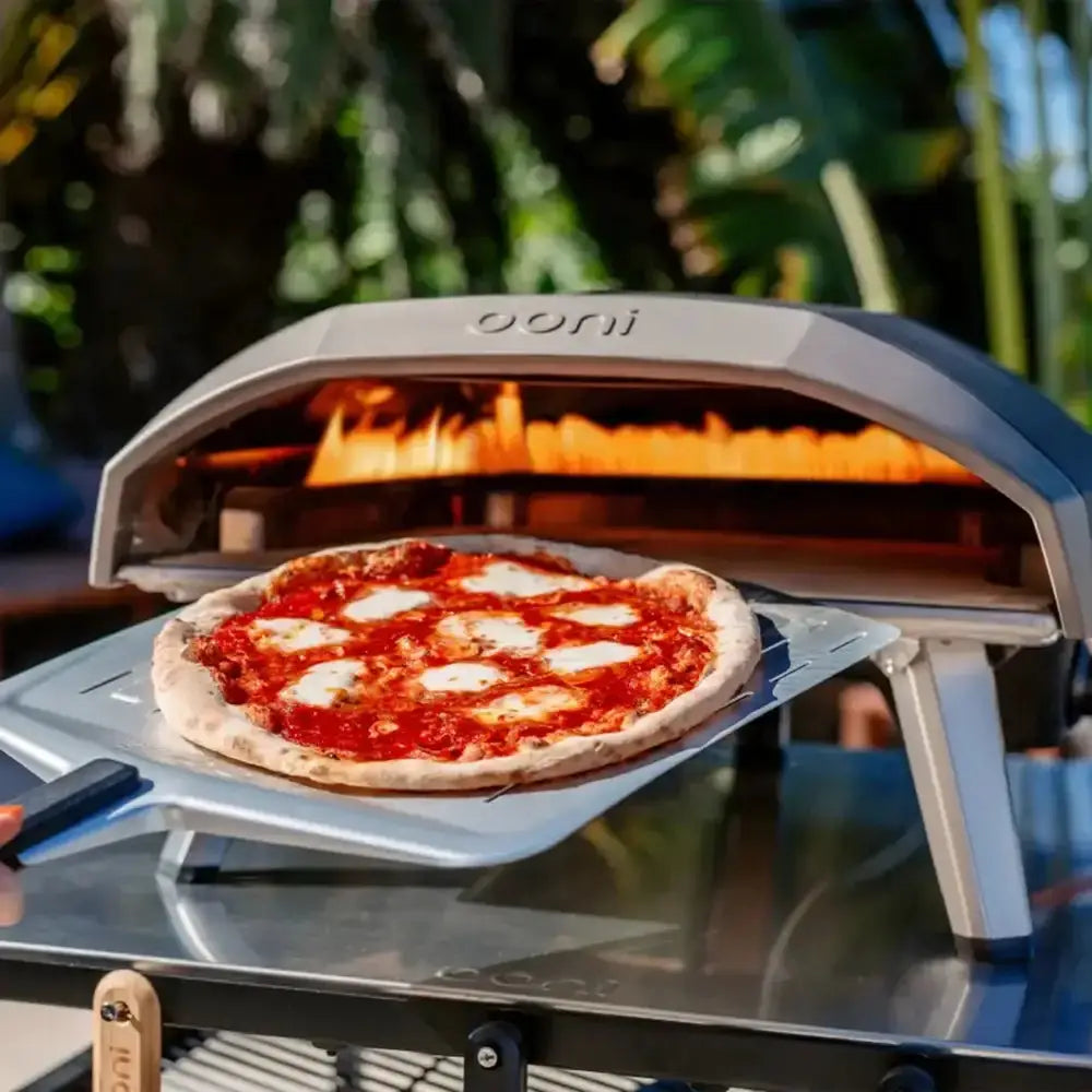Ooni pizza oven with a pizza inside, outdoors.