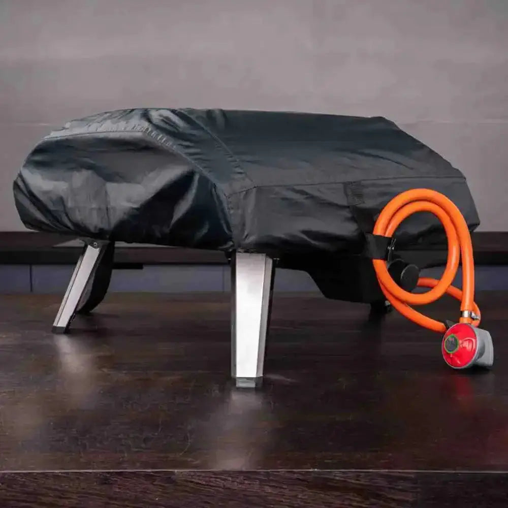 Black outdoor furniture cover with an orange hose and red valve on a wooden floor.