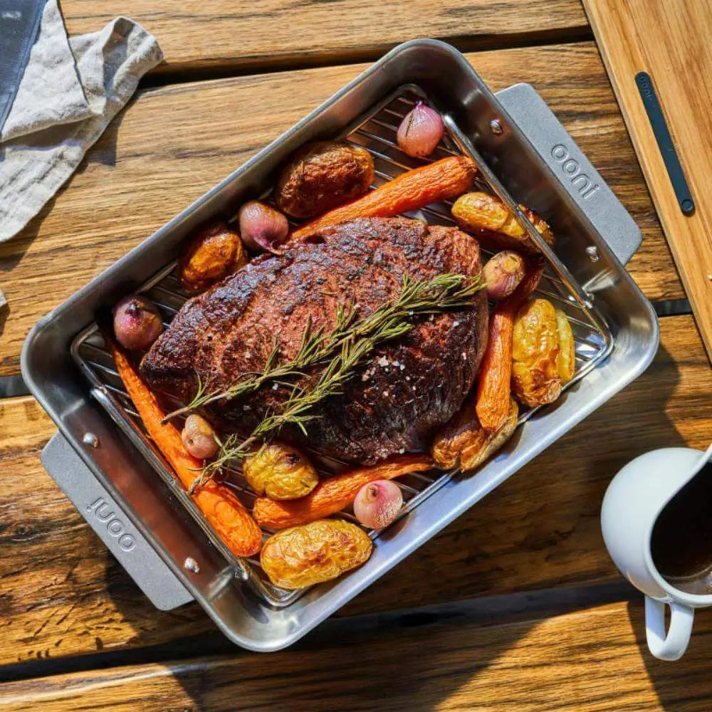 Roasted meat with vegetables on a grill pan on a wooden table