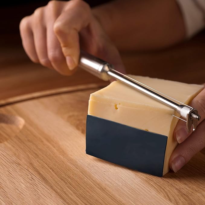 Person using a cheese slicer to cut a block of cheese on a wooden board