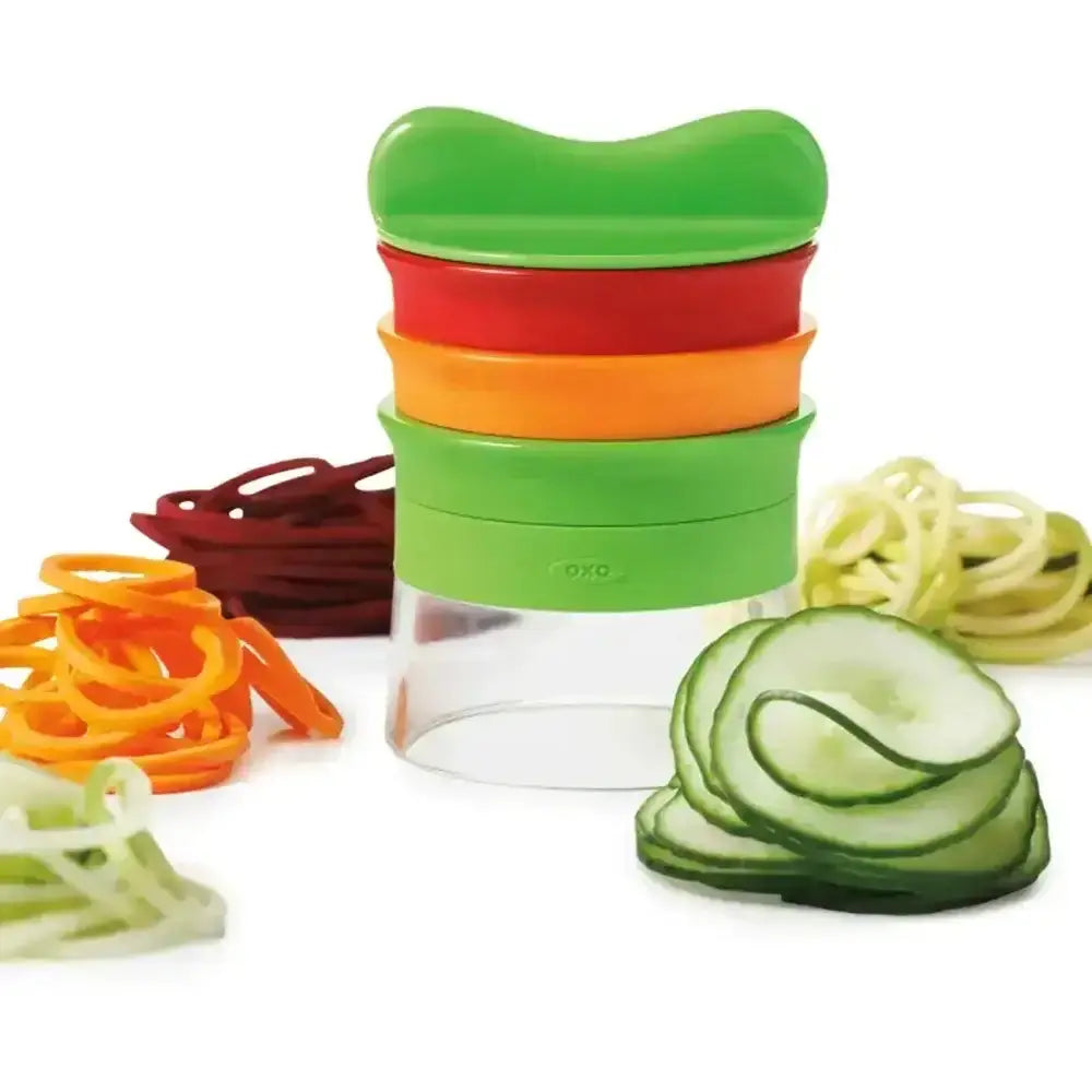 Green spiralizer with sliced vegetables on a white background