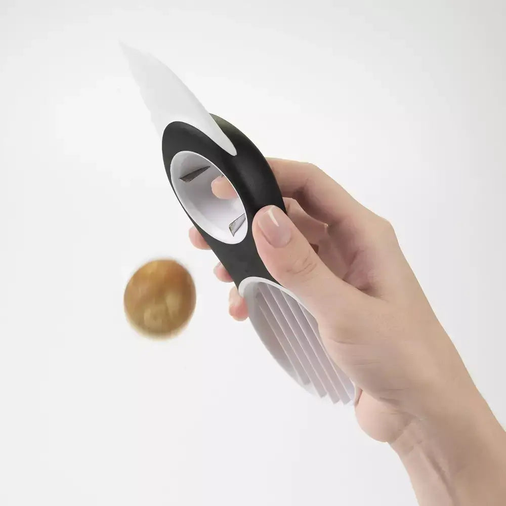 A hand using the oxo avocado slicer to remove the pip of an avocado