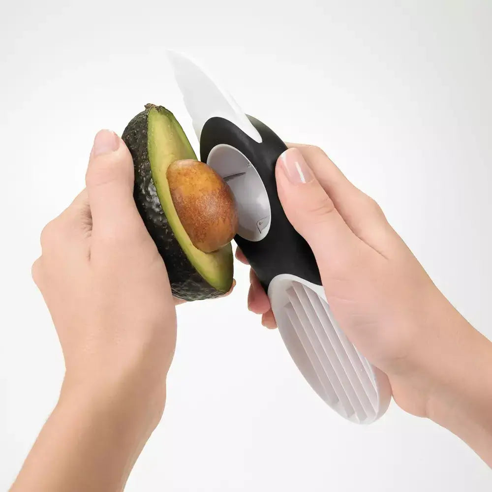 Hands using the oxo avocado slicer to remove the pip 