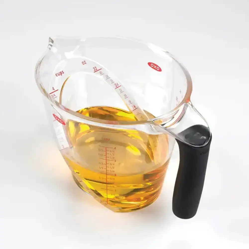 Measuring cup with oil on a white background