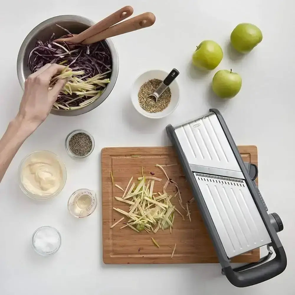 Person preparing food with a mandoline slicer on a white surface