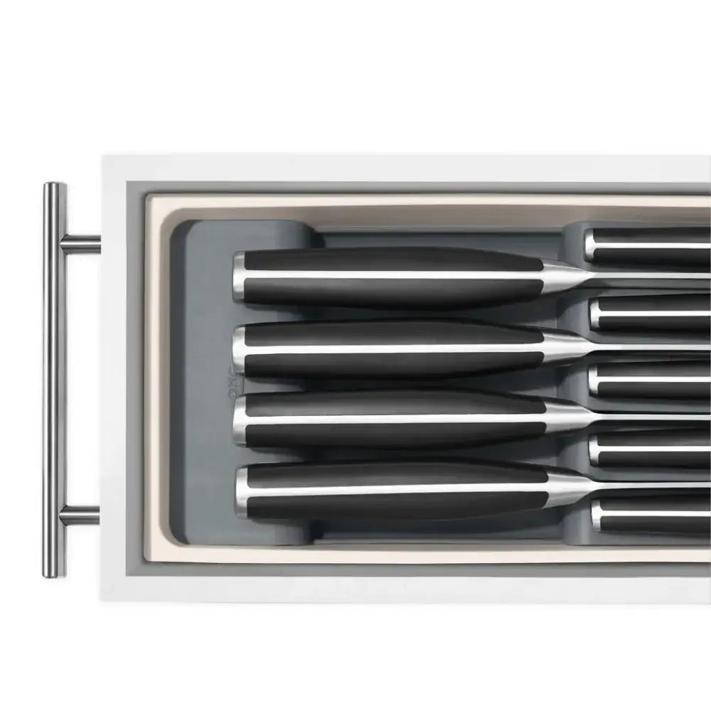 OXO Good Grips knife drawer organizer with black handles and stainless steel blades in gray tray inside white drawer