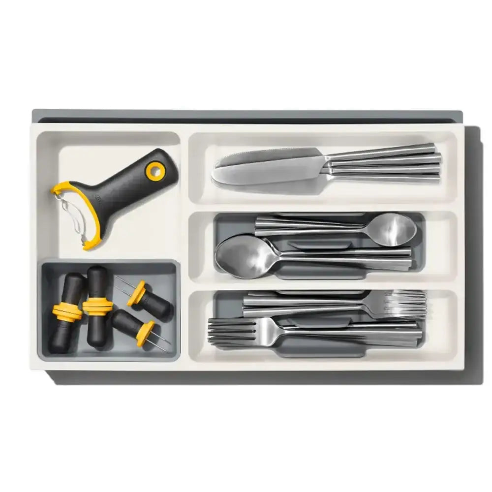 Set of silver cutlery with black handles in a gray organizer on a white background