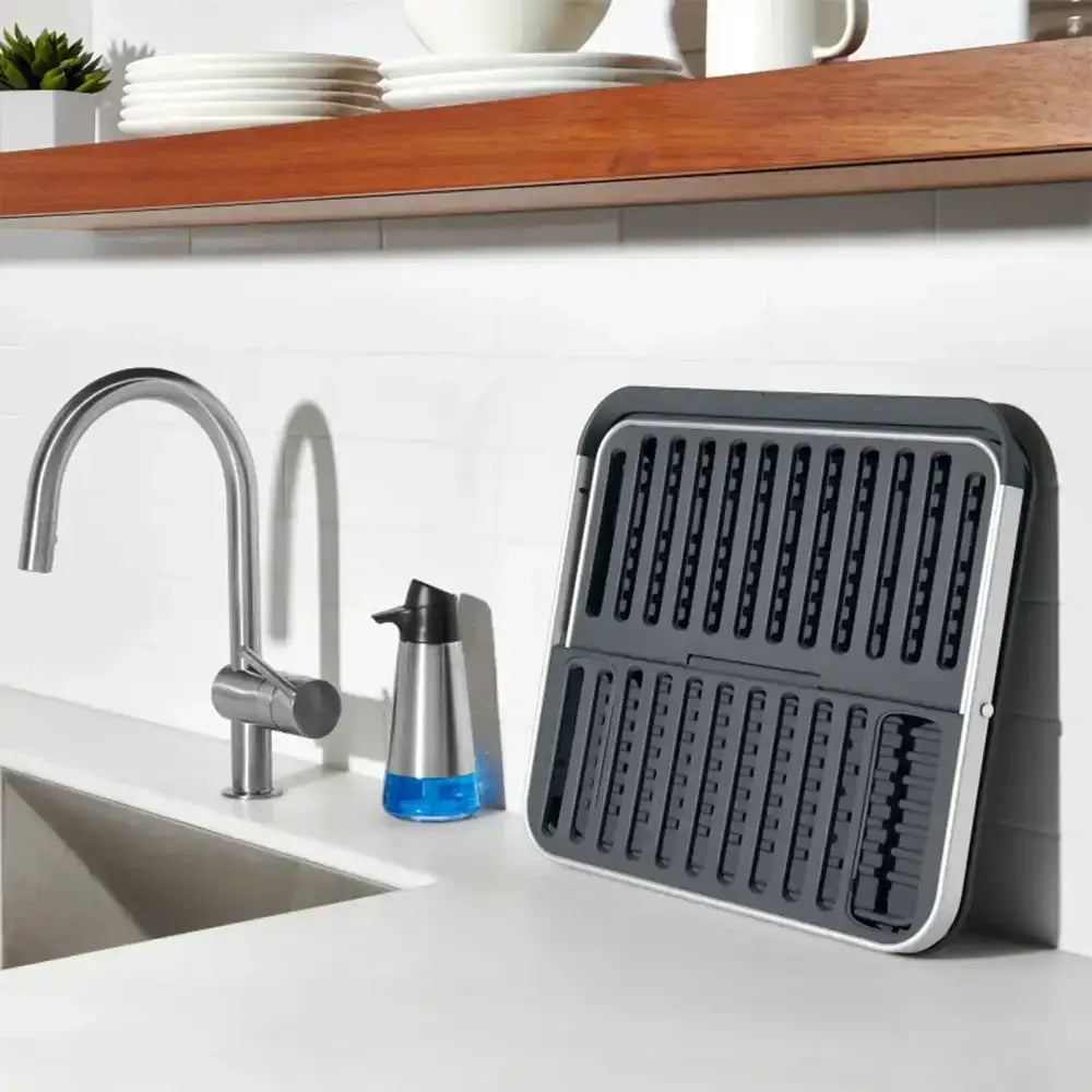 Gray dish drying rack on a kitchen counter with sink and faucet in the background