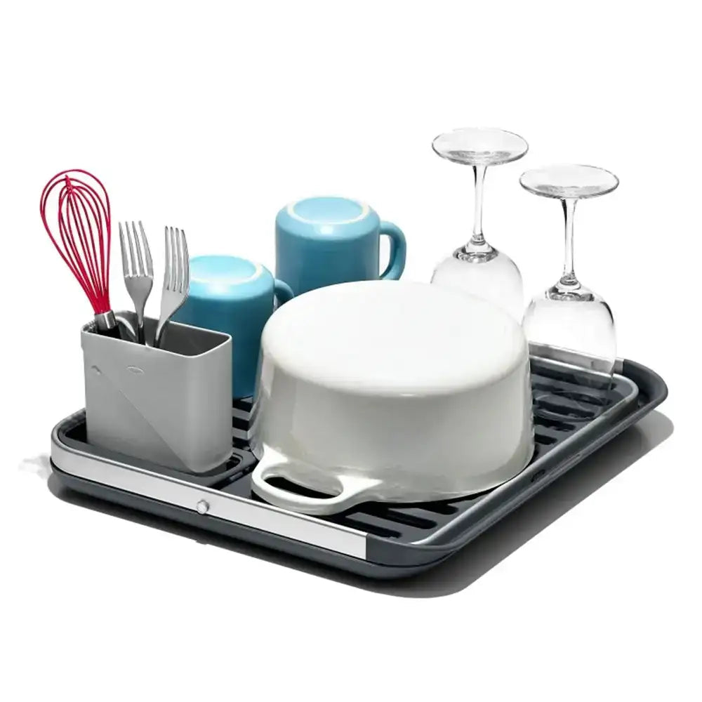Dish drying rack with dishes, utensils, and glasses on a white background