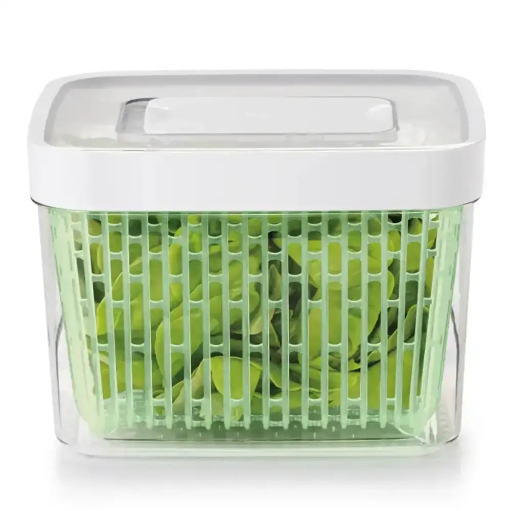 Green salad spinner with a white handle on a white background