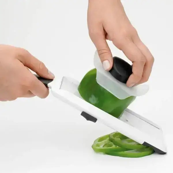 Person using a green pepper slicer on a white background