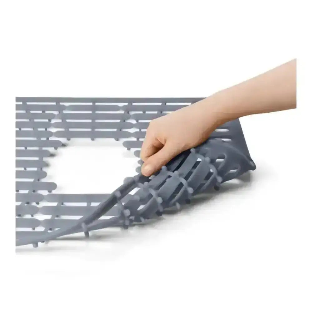 Gray kitchen drain cover with a hand lifting it on a white background