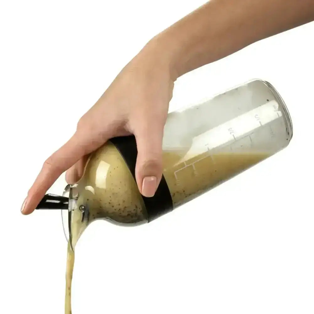Hand pouring a liquid from a glass bottle with a white background