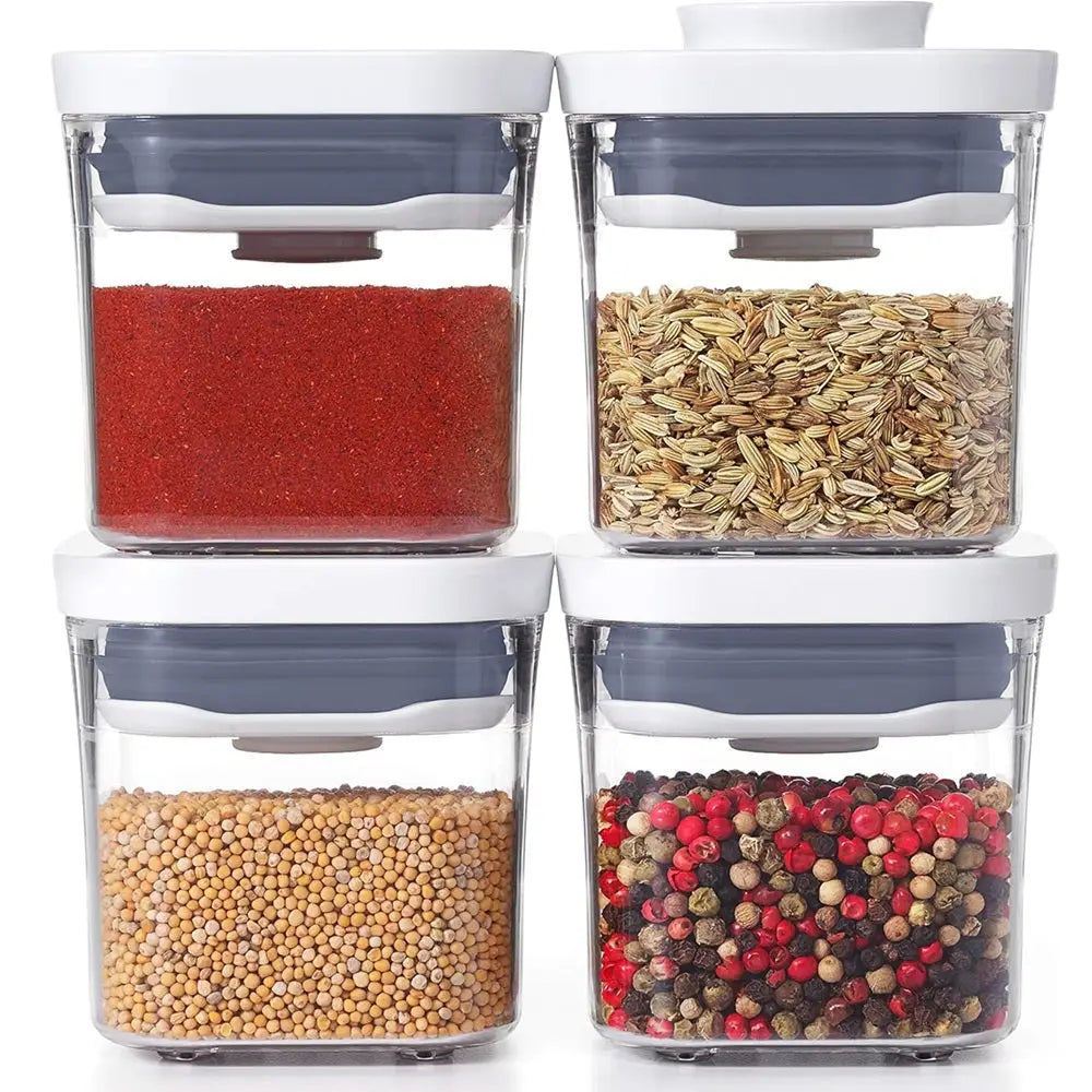 Set of four clear containers with lids, each filled with different types of grains and spices.