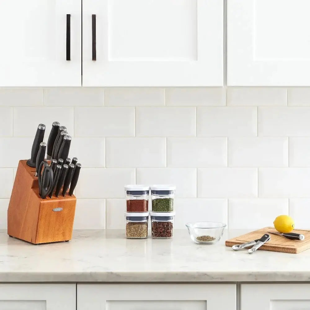 Knife block with knives, spice jars, and a cutting board on a kitchen counter.
