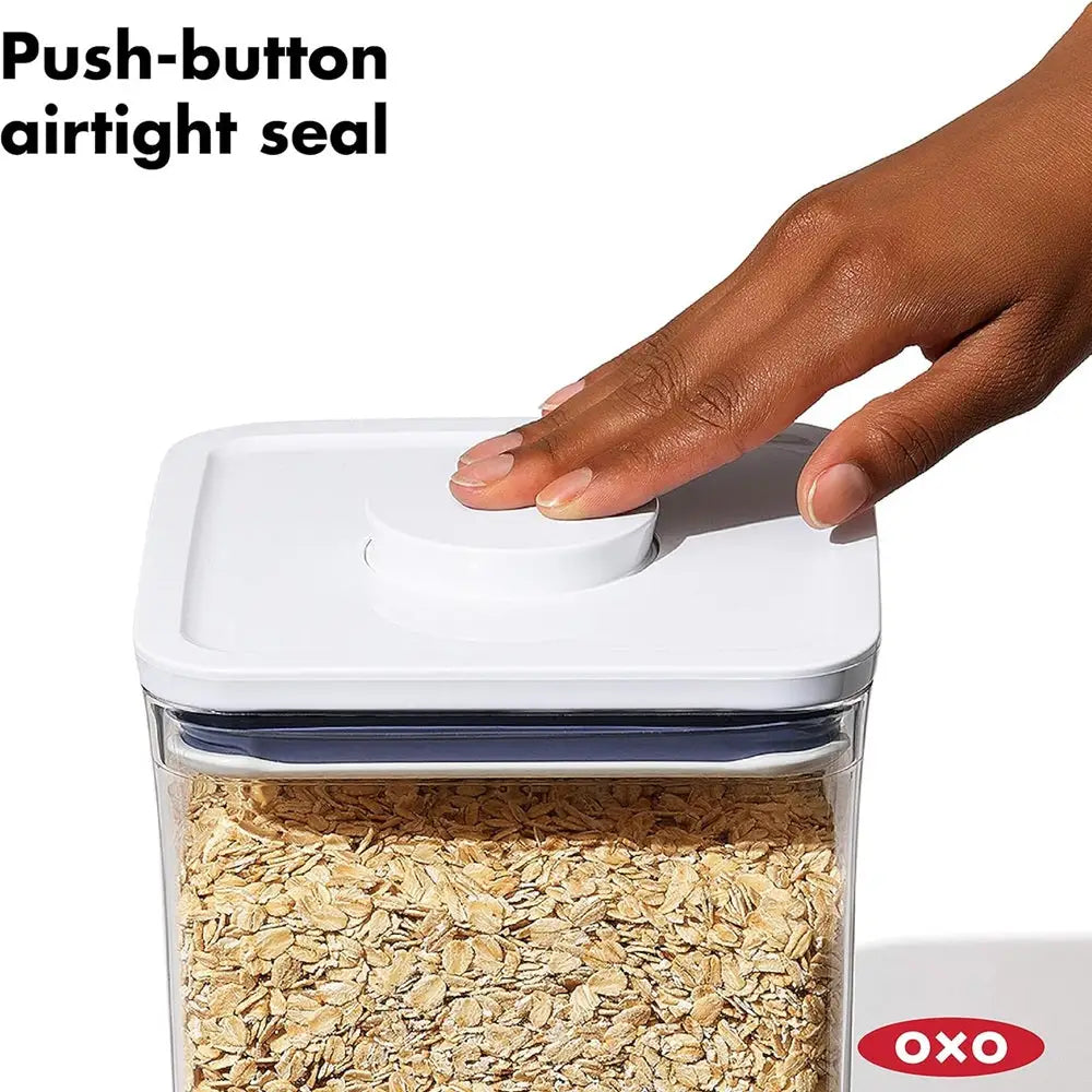Hand pressing a push-button airtight seal on an OXO container filled with oats.