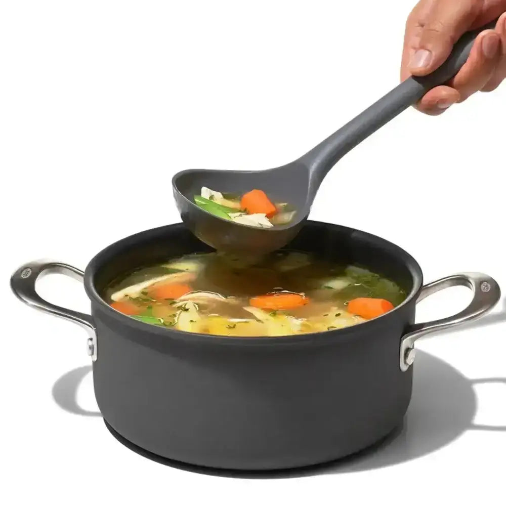 Person ladling soup from a pot with a ladle