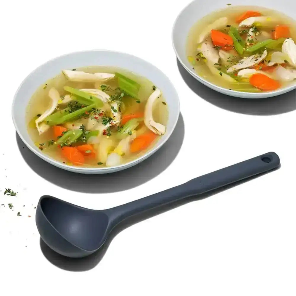 Two bowls of soup with vegetables and a ladle on a white background