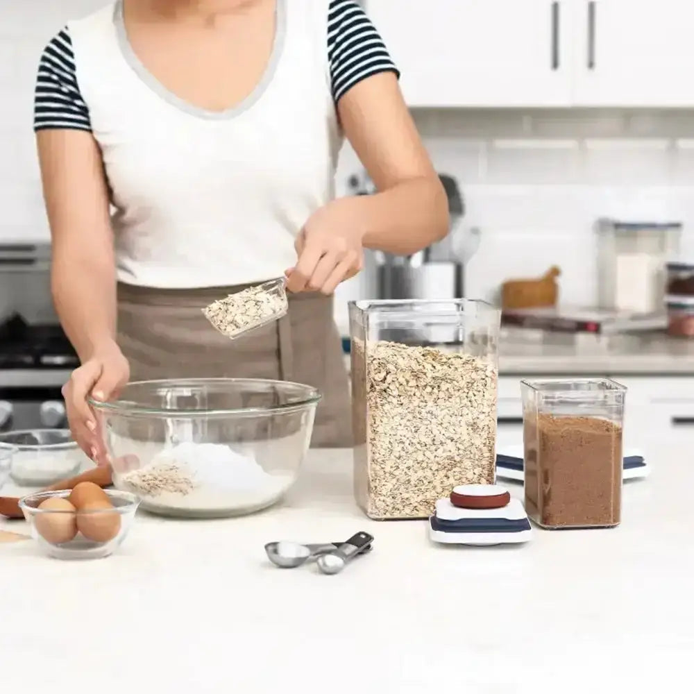 Person preparing ingredients in a kitchen with various containers and utensils.