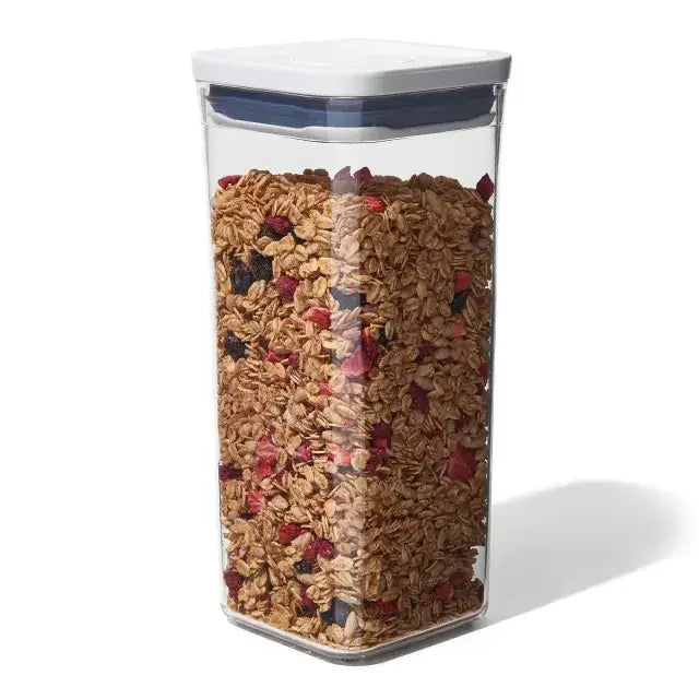 Clear container filled with granola and berries on a white background