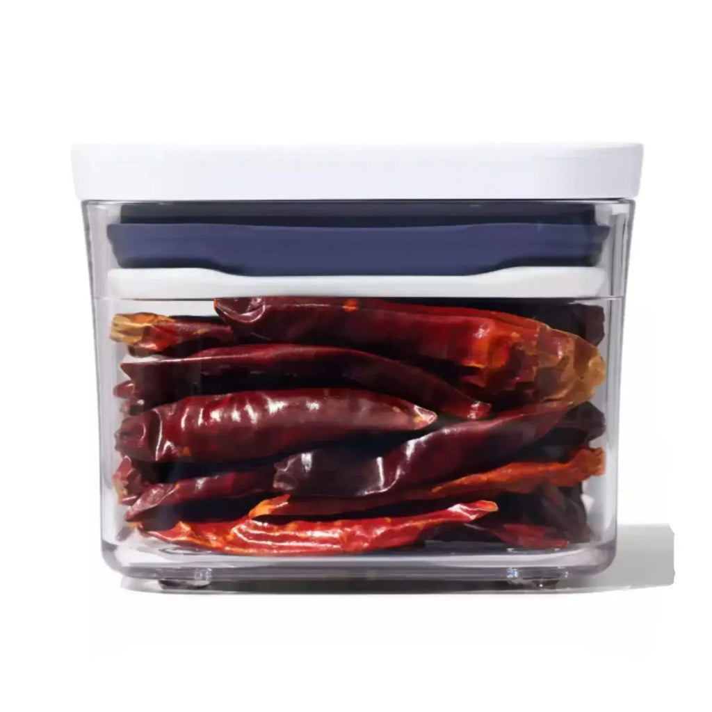 Clear container with dried red chili peppers inside on a white background