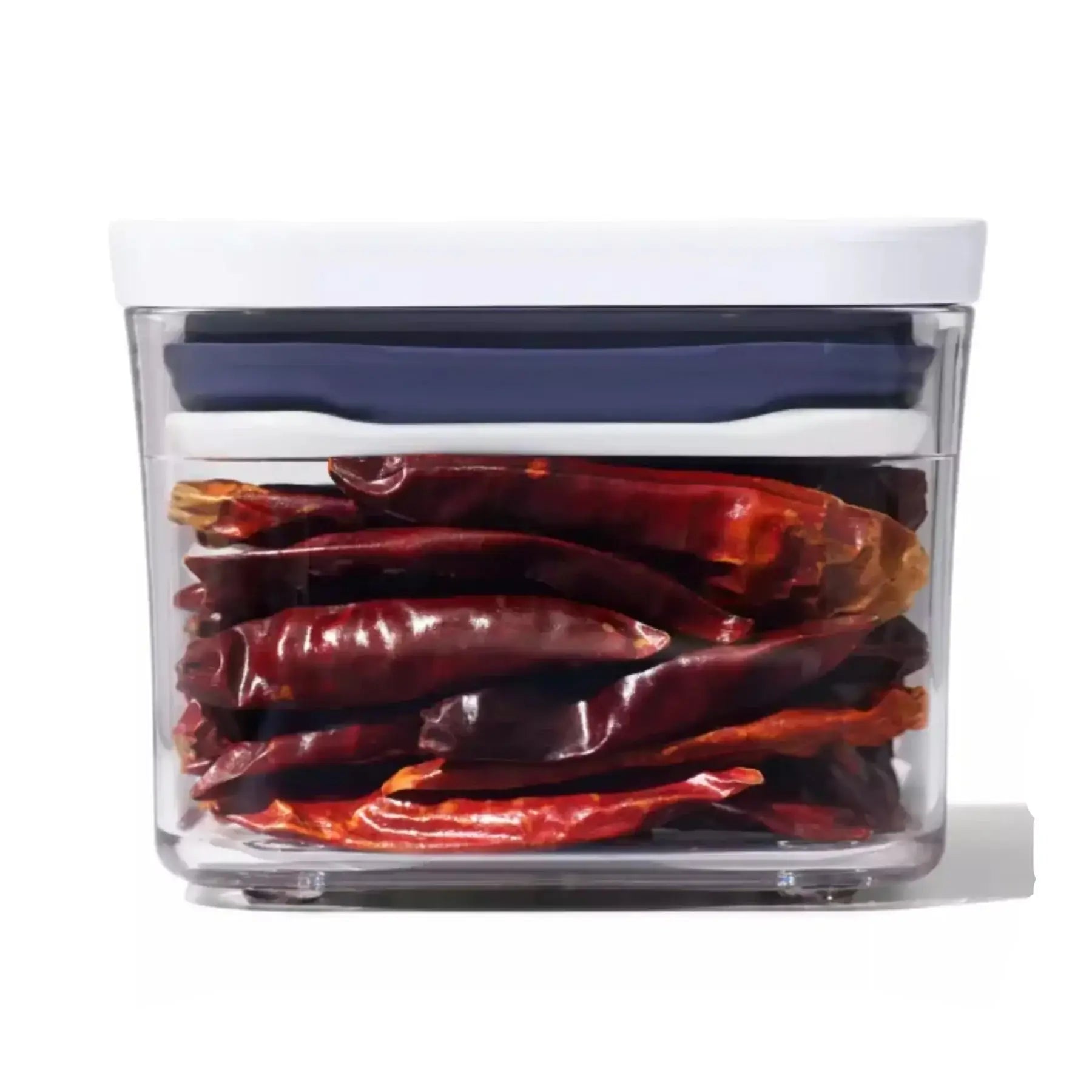 Clear container with dried red chili peppers inside on a white background