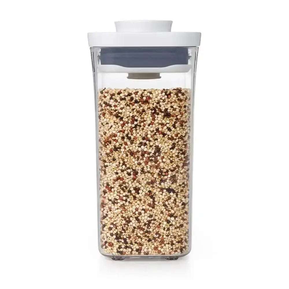 Clear container with lid filled with multicolored quinoa on a white background