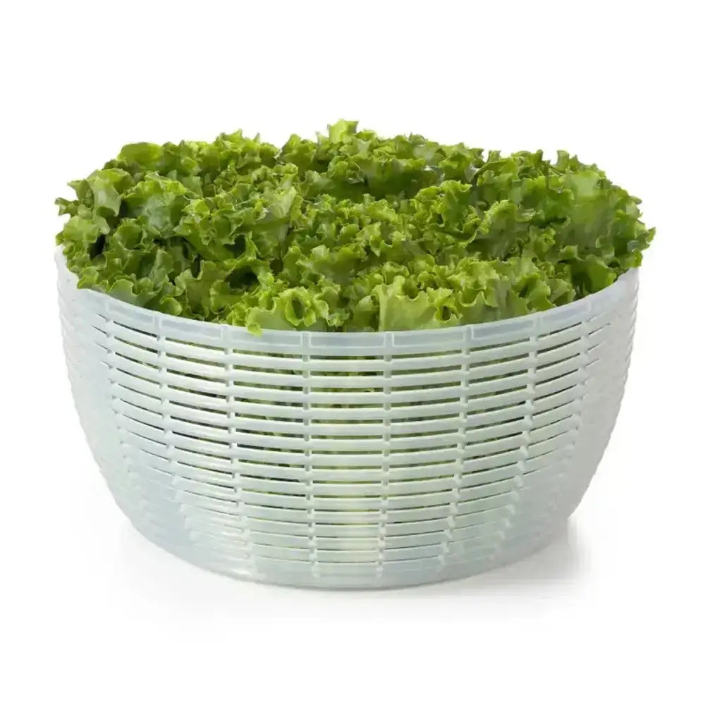 Green leafy vegetables in a white plastic colander on a white background