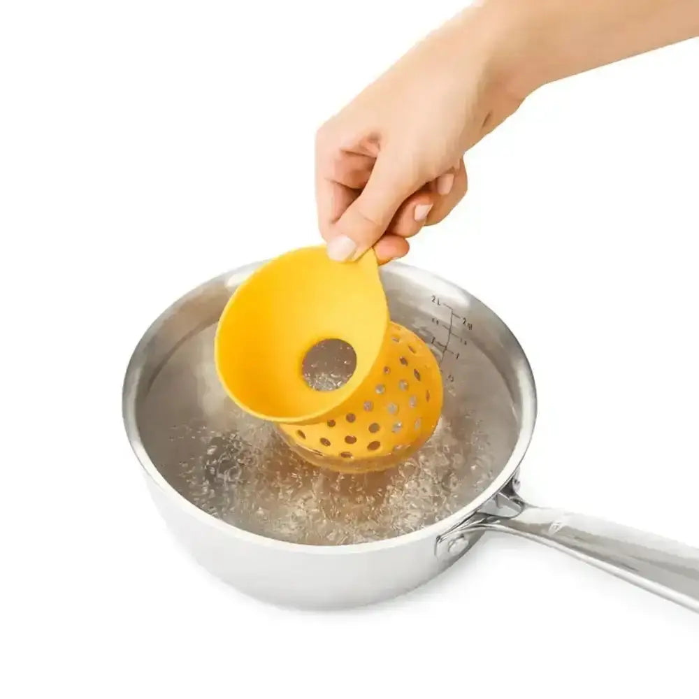 Yellow egg poacher being used in a pot on a white background