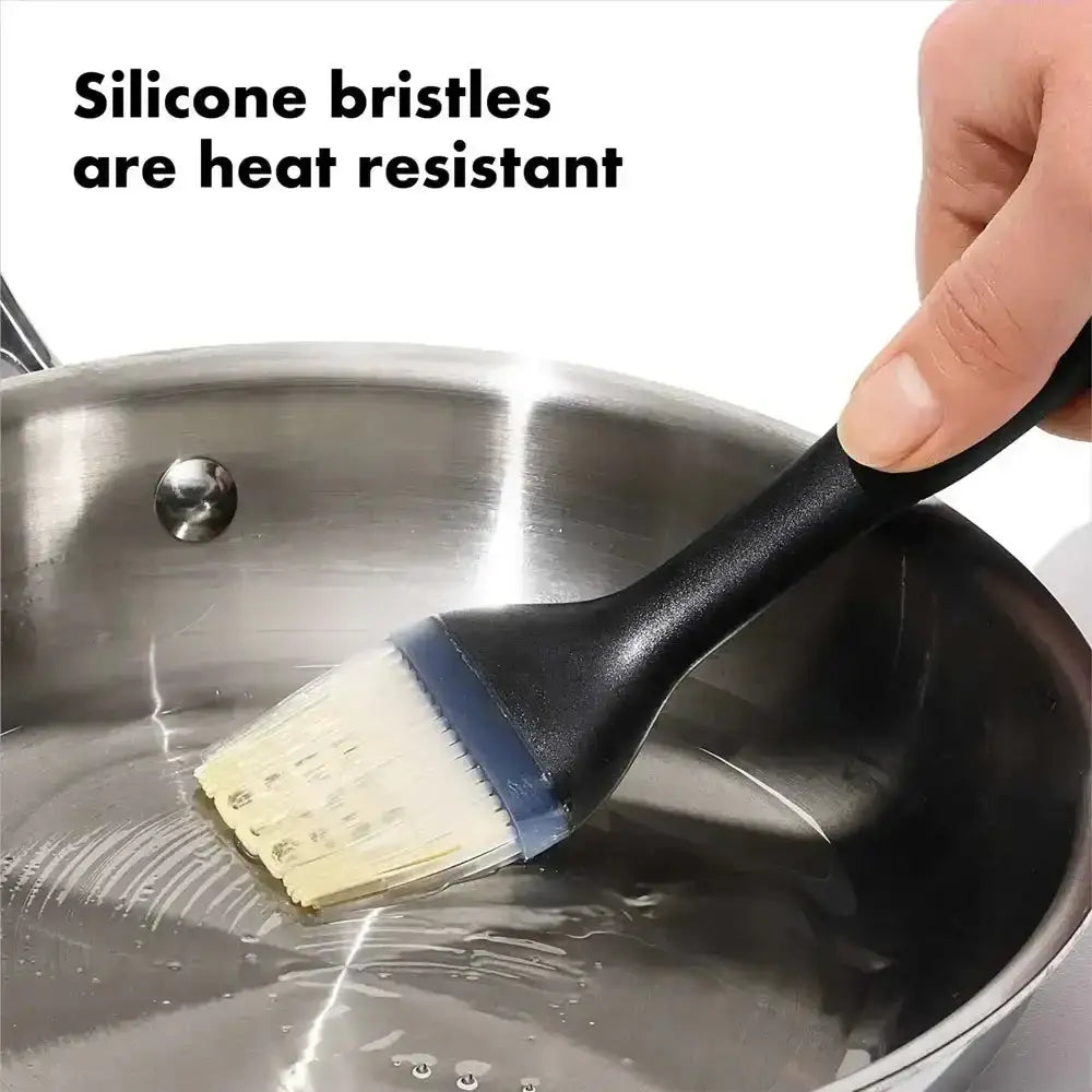 Silicone brush with heat-resistant bristles being used on a hot pan