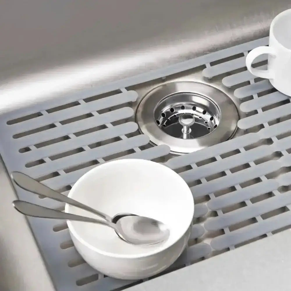 White bowl with spoons on a kitchen sink grid