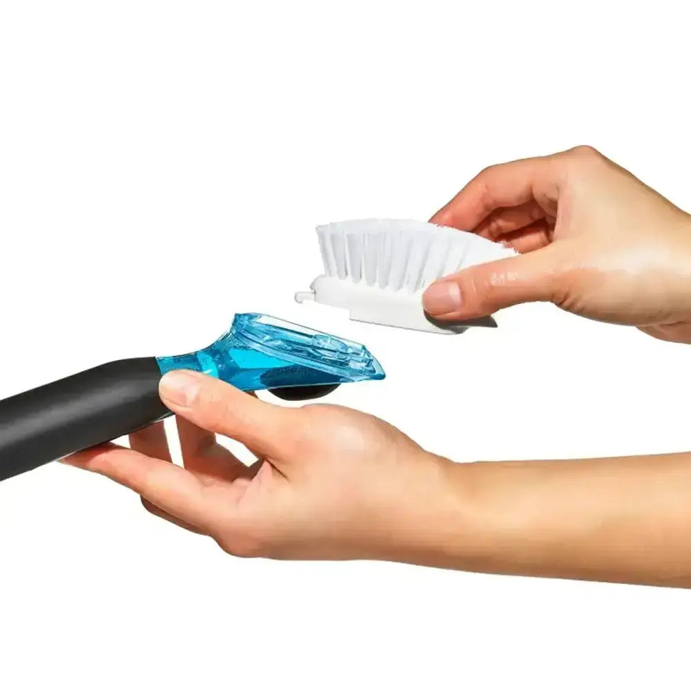 Person holding a cleaning brush with a blue base and white bristle head on a white background