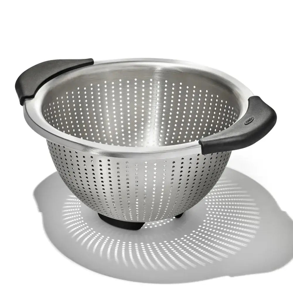 Stainless steel colander with black handles on a white background