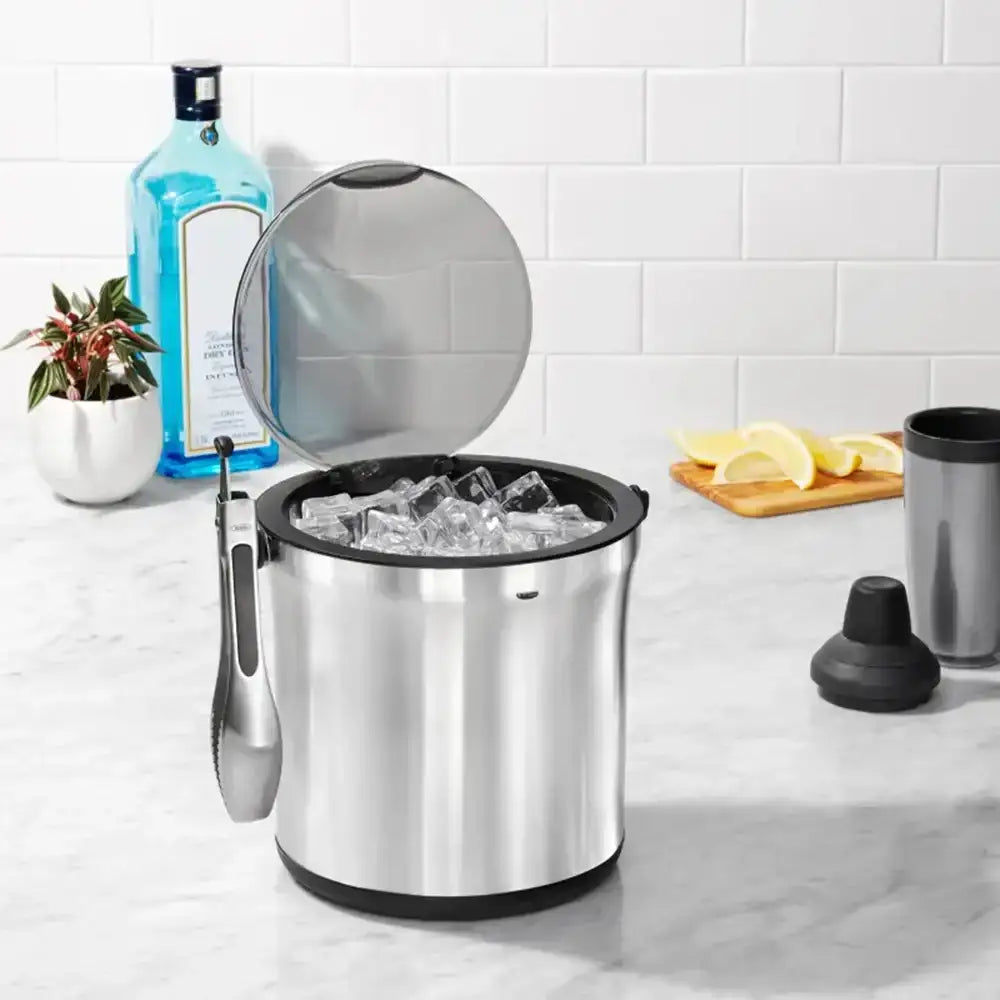 Stainless steel ice bucket with ice on a kitchen counter