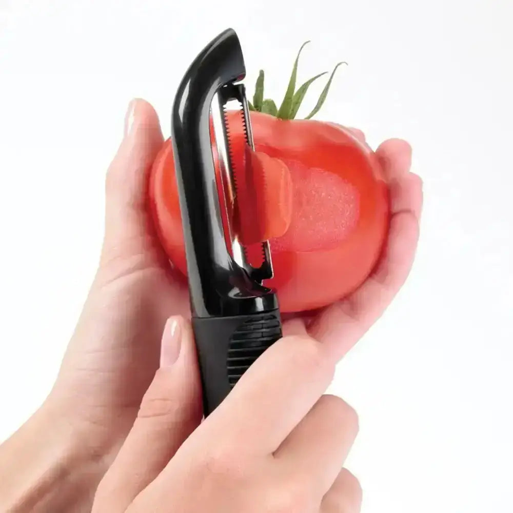 Person using a tomato peeler on a red tomato with a white background