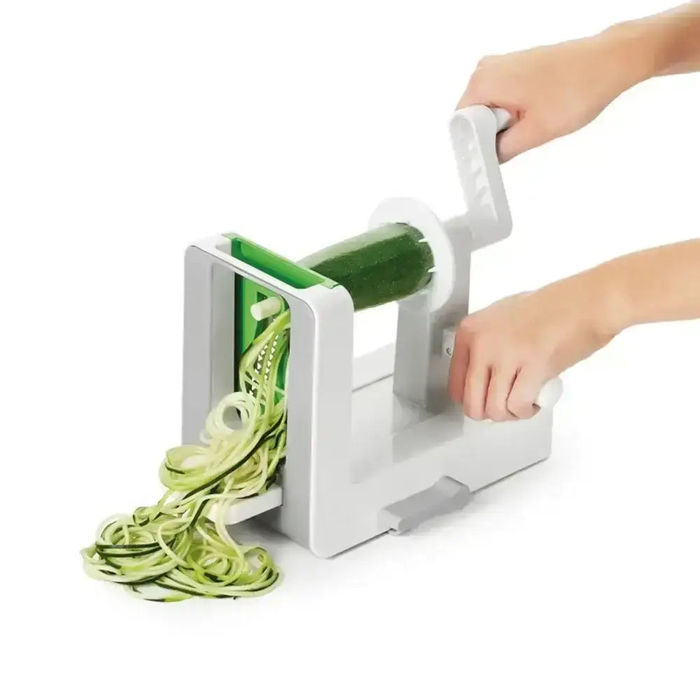 Hand using a spiralizer to create zucchini noodles on a white background