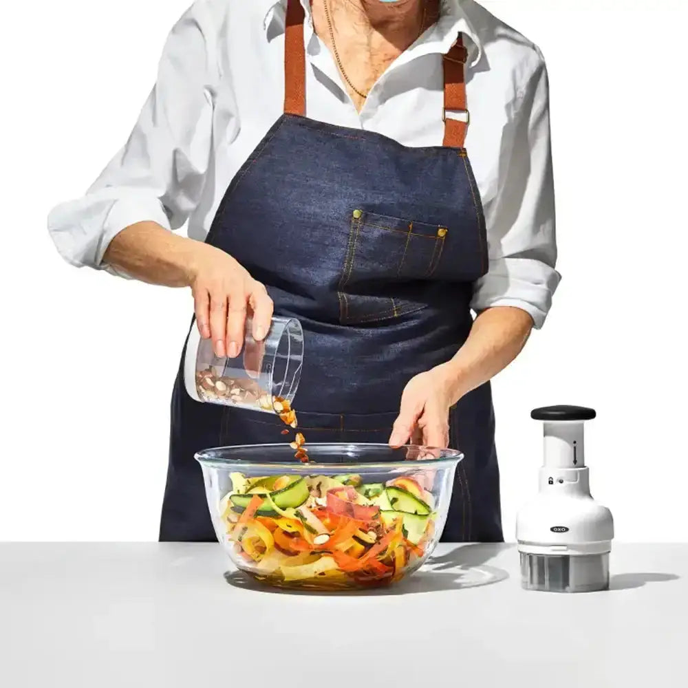 Person preparing a salad with a food chopper on a white background