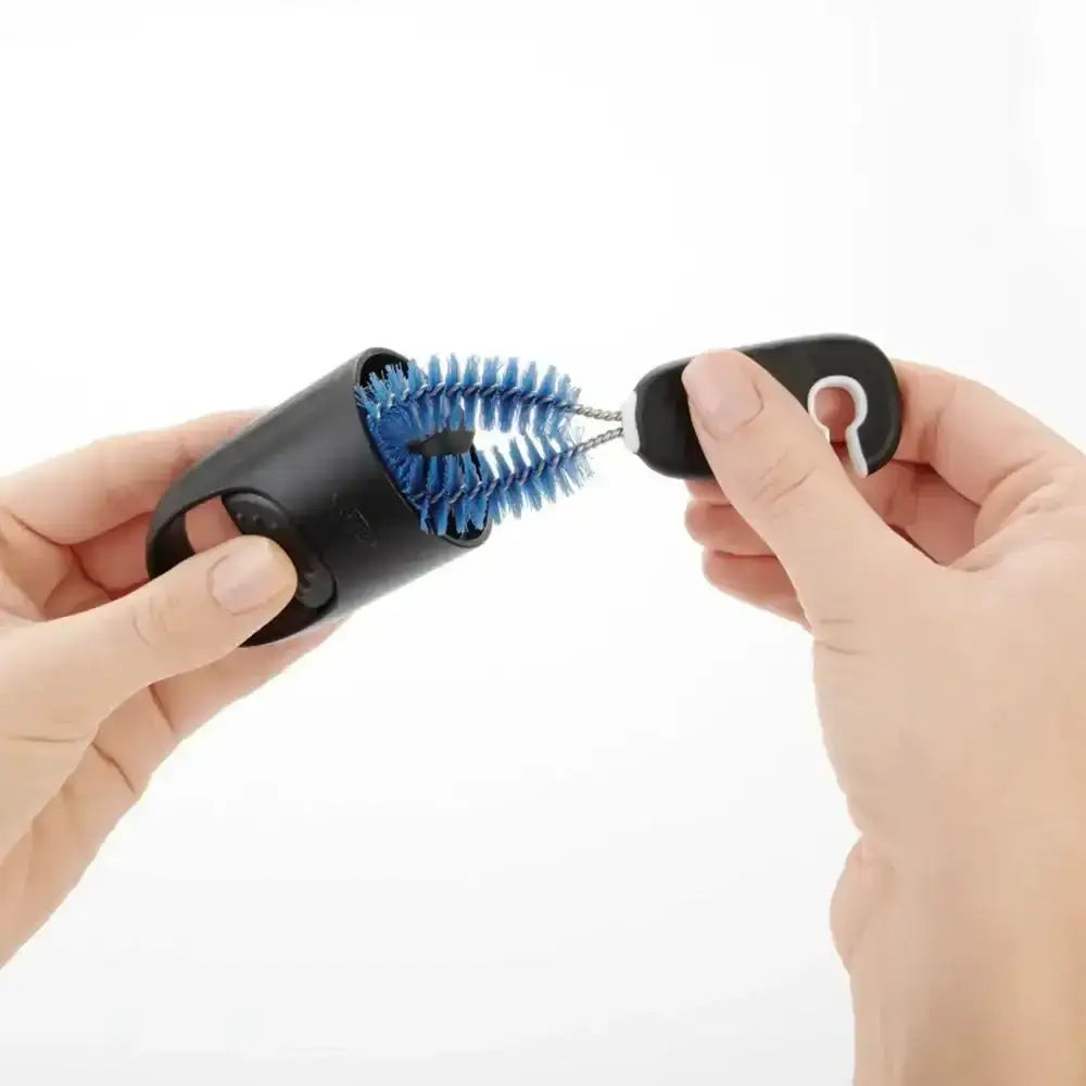 Hand holding a black and blue grooming brush on a white background